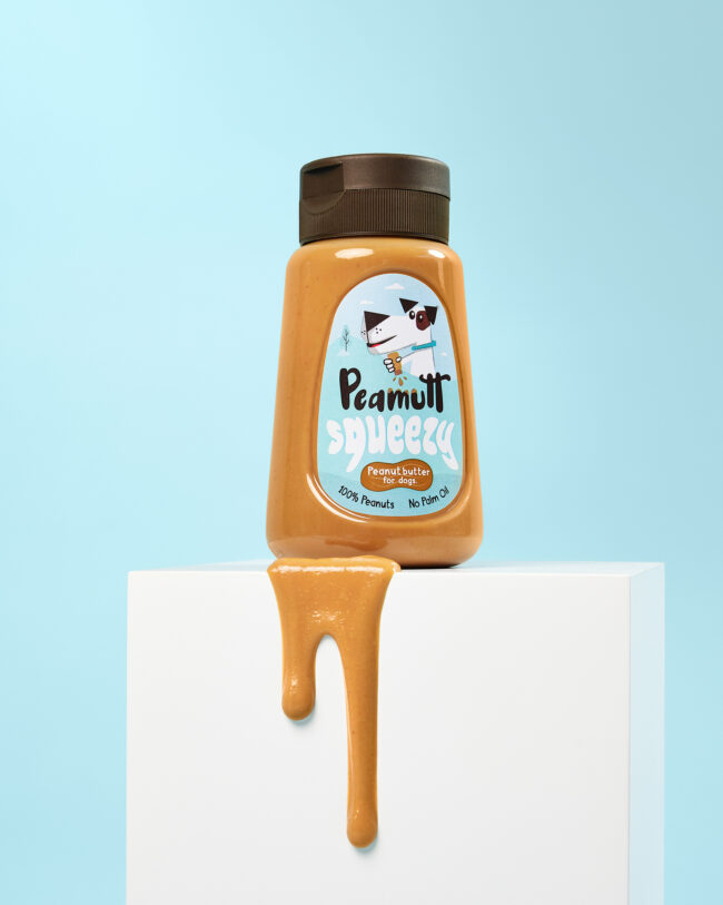 Studio product photography of a peanut butter dog treat bottle for a commercial pet brand campaign