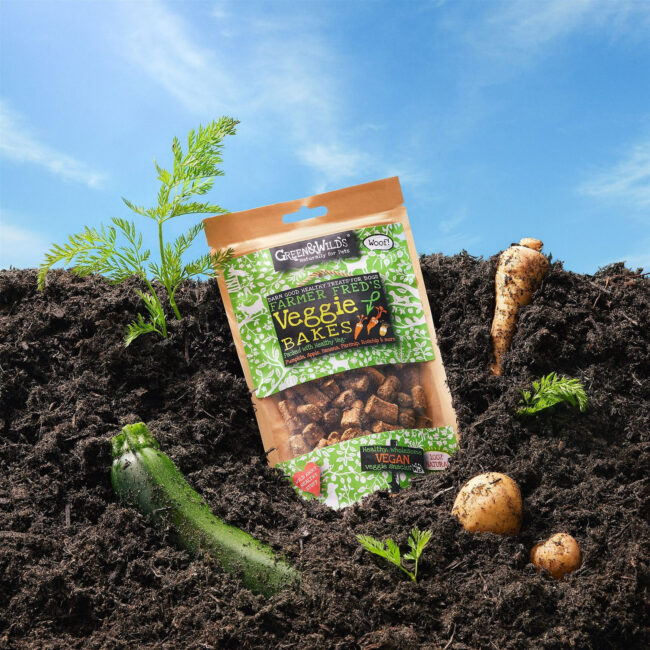 Creative studio product photography of pet food packaging styled in soil with vegetables for a commercial pet food campaign green & wilds