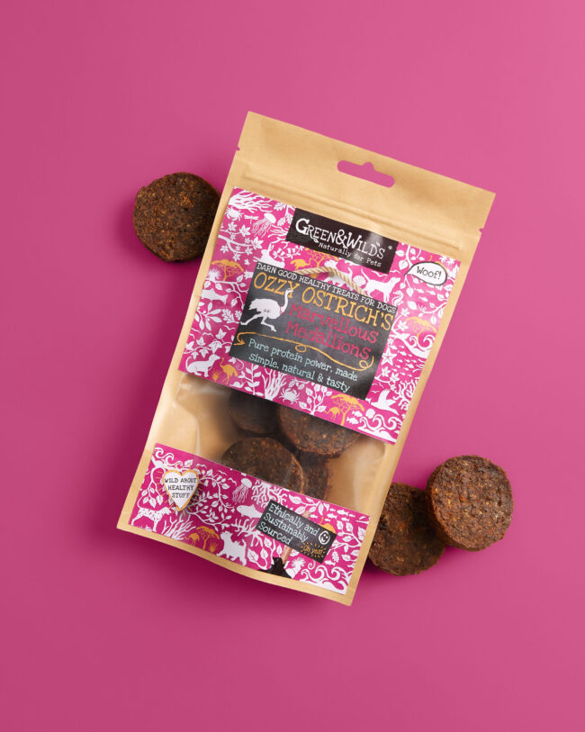 Studio product photography of pet treat packaging against a pink background for a commercial pet food campaign green & wilds