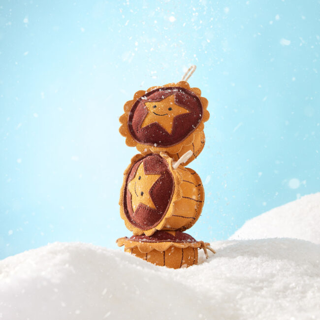 Studio product photography of stacked pet treats styled in a winter-themed set for a commercial pet brand campaign