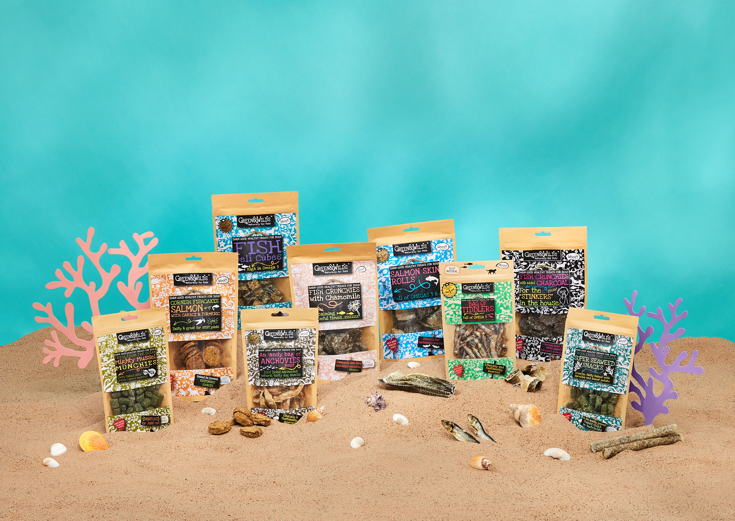 Studio photography of a pet food product range styled on a beach-themed set for a commercial pet brand campaign green & wilds